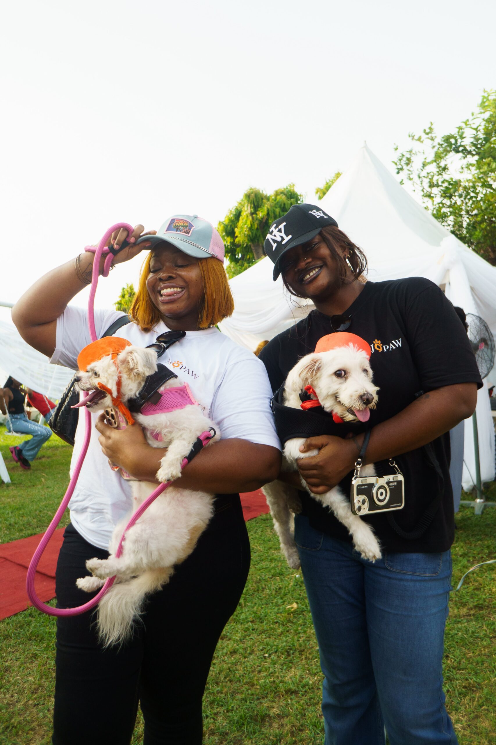 Smiling ladies with dogs in their hands in an ajopaw shirt